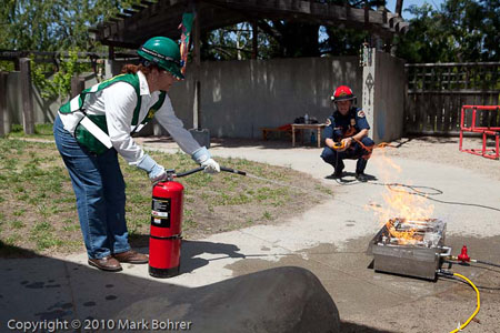 Saratoga CERT volunteer Madeleine extinguishing the fire while Rob Hecocks watches during West Valley College / Saratoga CERT disaster preparedness exercise